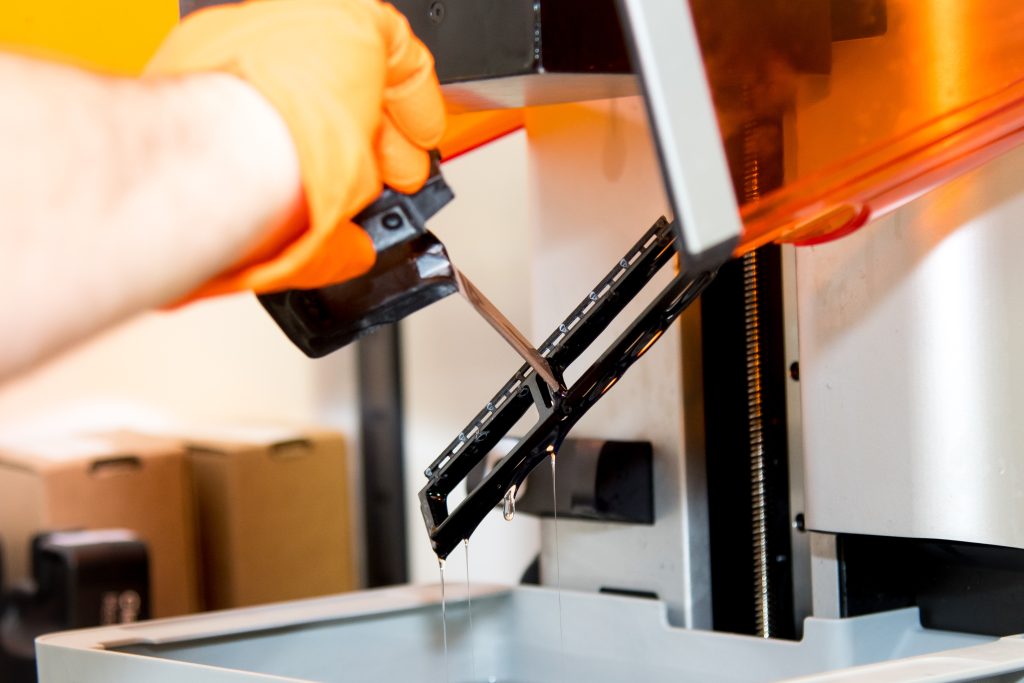 A gloved hand holding up a 3D printed part.