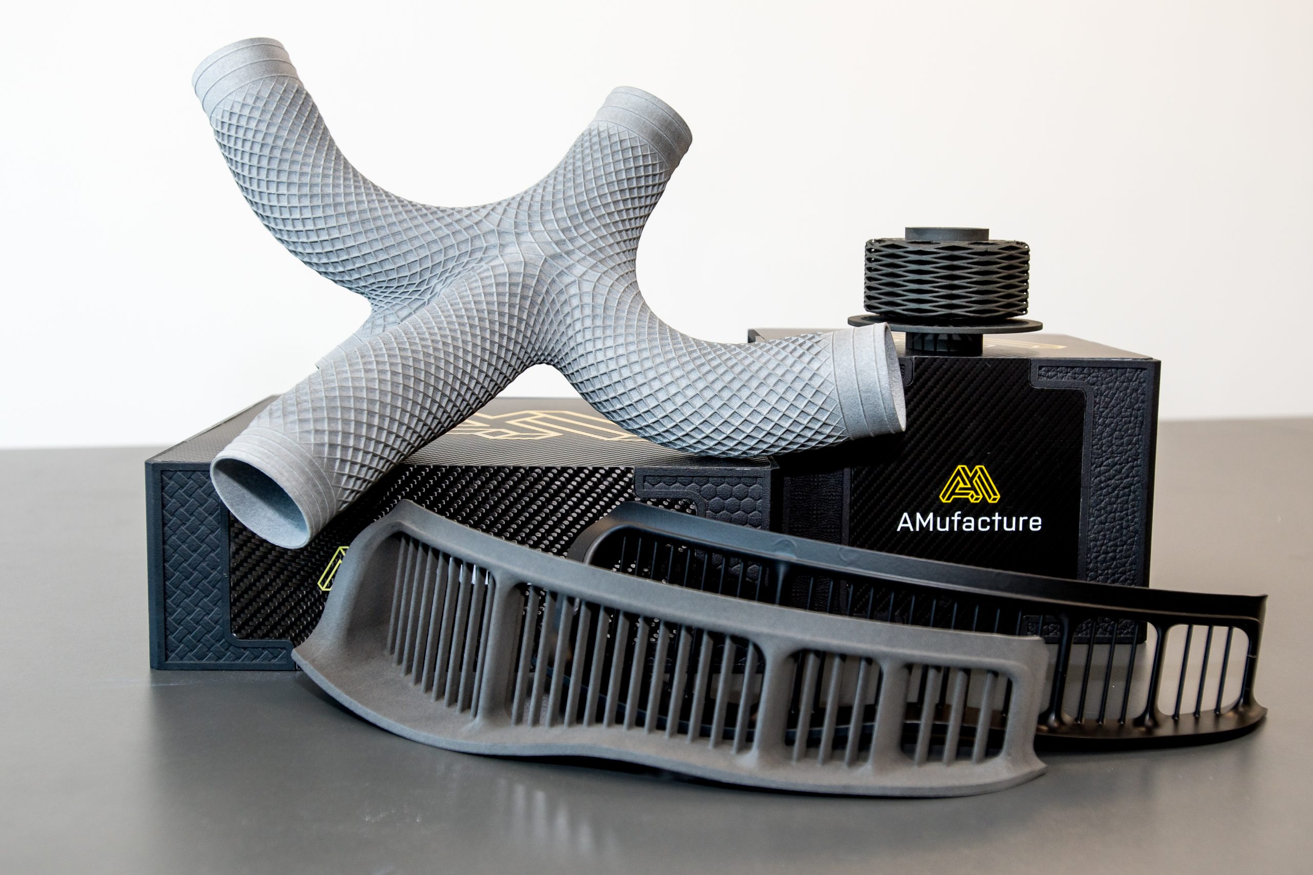 A collection of 3D printed components. Two pieces of curved grill and a tube with two other nozzles coming off of either side.
